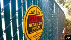 FILE - A warning sign marks a natural gas pipeline outside a compressor station on Oct. 25, 2021, in Dalworthington Gardens, Texas.