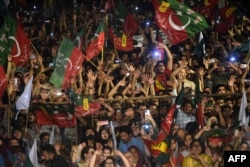 Supporters of the Tehreek-e-Insaf (PTI) party of dismissed Pakistan's prime minister Imran Khan, wave party flags as they take part in a rally in his support in Karachi, April 10, 2022.