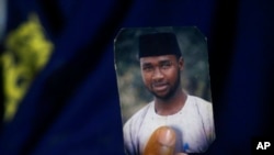 FILE - Amina Ahmed, the wife of Mubarak Bala, an atheist recently sentenced to prison on charges of blasphemy in Nigeria, holds his picture in her home in Abuja, Nov. 21, 2021.