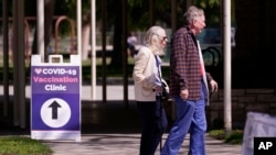 FILE - People leave a testing and vaccination clinic for COVID-19, March 30, 2022, in Long Beach, Calif. 