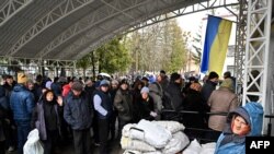 FILE - People queue to buy mainly medicine and other goods in the town of Bucha, northwest of Kyiv, Ukraine, April 3, 2022.