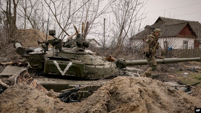 Lính Ukraine bước cạnh xác một chiếc xe tăng Nga bị bỏ lại ở Andriivka