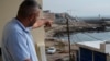 A Lebanese man points to the beach in Batroun, northern Lebanon, where Lebanese officials say a group of armed men landed and took away a ship captain, Nov. 2, 2024. 