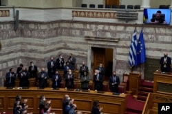 Greek Cabinet and lawmakers applaud as Ukrainian President Volodymyr Zelenskyy, on the screen, thanks after addressing Greek Parliament in Athens, Greece, April 7, 2022.