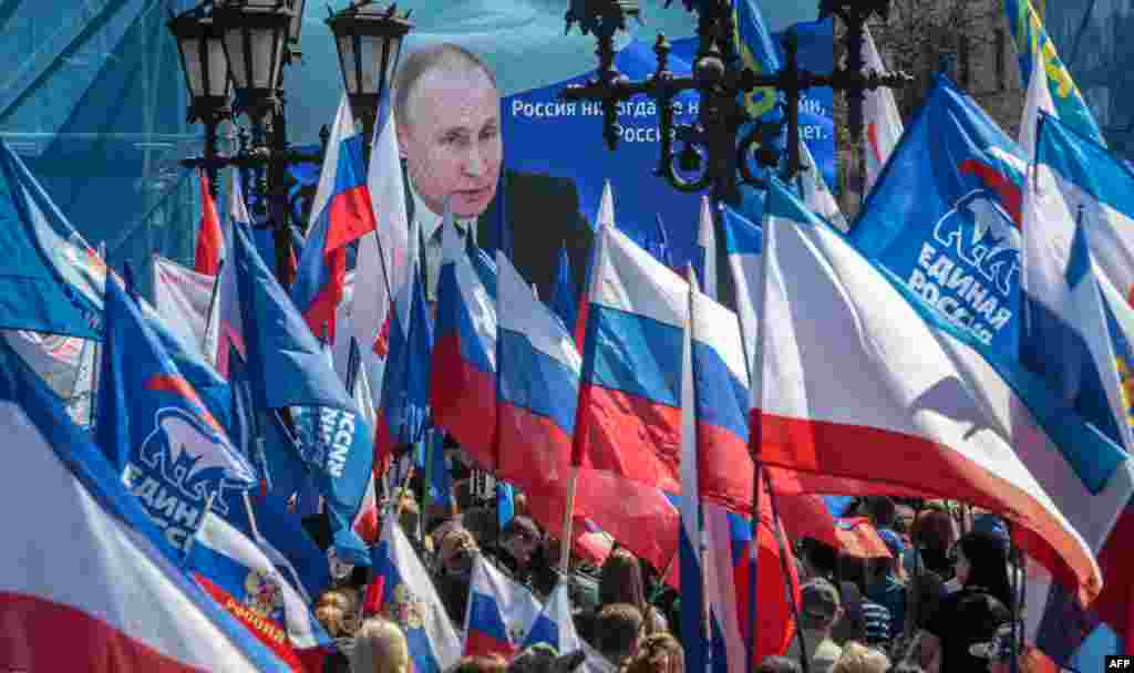 People wave flags during a rally in support of the Russian military operation in Ukraine, in Simferopol, Crimea. (Photo by AFP)