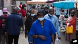 FILE - A woman wearing a mask to protect against the coronavirus walks through the busy Bara Taxi Rank in Soweto, South Africa, April 5, 2022.