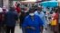 FILE - A woman wearing a mask to protect against the coronavirus walks through the busy Bara Taxi Rank in Soweto, South Africa, April 5, 2022.
