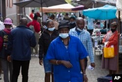 FILE - A woman wearing a mask to protect against the coronavirus walks through the busy Bara Taxi Rank in Soweto, South Africa, April 5, 2022.