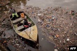 Dua pekerja dari pembangkit listrik tenaga air Ruzizi I melakukan tur inspeksi di Sungai Ruzizi untuk melihat tingkat sampah plastik di sekitar bendungan pembangkit di Bukavu, Republik Demokratik Kongo timur, pada 17 Maret 2022. (Guerchom NDEBO / AFP)