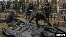 Cemetery employees and police investigators work with bodies of civilians collected from streets and brought to a local cemetery, in the town of Bucha, outside Kyiv, Ukraine April 6, 2022.