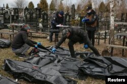 Cemetery employees and police investigators work with bodies of civilians collected from streets and brought to a local cemetery, in the town of Bucha, outside Kyiv, Ukraine, April 6, 2022.