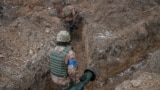 A Ukrainian service member walks along a trench with a Javelin missile system a at a position on the front line in the north Kyiv region