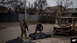 Soldados ucranianos recuperan los restos de cuatro civiles de un vehículo calcinado en Bucha, a las afueras de Kiev, Ucrania, el martes 5 de abril de 2022.
