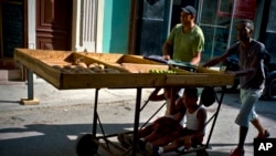 Fruit and vegetable vendors push their cart after a day's work, as two boys ride under the cart in Havana, May 31, 2017. The number of officially self-employed Cubans has grown by a factor of five since President Raul Castro launched limited market-based reforms in 2010.