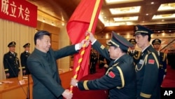 中共領導人習近平在北京舉行的中國人民解放軍戰區成立大會上向火箭軍將領、中國防長魏鳳和（中）授予軍旗。（2015年12月31日）