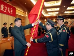 中共领导人习近平在北京举行的中国人民解放军战区成立大会上向火箭军将领、中国防长魏凤和（中）授予军旗。（2015年12月31日）