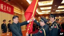 资料照片：2015年12月31日，中国领导人习近平在北京举行的中国人民解放军战区成立大会上向火箭军将领、中国防长魏凤和（中）授予军旗。（美联社照片）