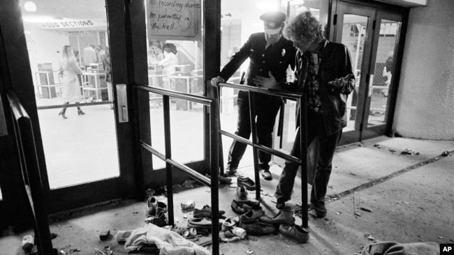 ARCHIVO - Un guardia de seguridad y otra persona no identificada miran el sitio donde varias personas murieron y otras resultaron heridas cuando quedaron atrapados en una multitud que ingresaba al Riverfront Coliseum de Cincinnati para un concierto de The Who el 3 de diciembre de 1979. (Foto AP/Brian Horton, archivo)