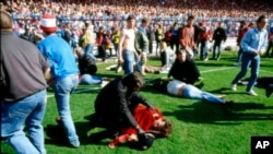 ARCHIVO - Guardias y simpatizantes atienden a los heridos en el campo del estadio de Hillsborough, en Sheffield, Inglaterra, el 15 de abril de 1989. (Foto AP, Archivo)