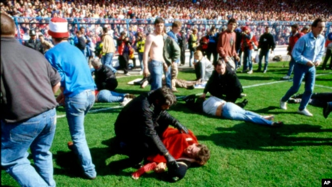 ARCHIVO - Guardias y simpatizantes atienden a los heridos en el campo del estadio de Hillsborough, en Sheffield, Inglaterra, el 15 de abril de 1989. (Foto AP, Archivo)