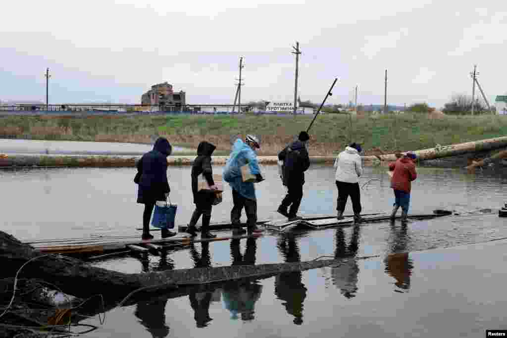 Sejumlah orang melintasi&nbsp;jembatan yang hancur setelah mereka mengumpulkan bantuan di tengah invasi Rusia ke Ukraina di wilayah Donbas timur di Bakhmut, Ukraina, 30 Oktober 2022.