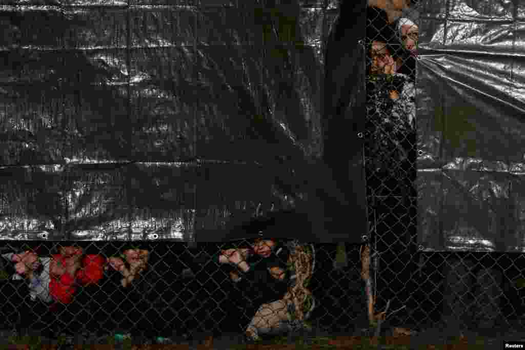 Detainees gesture through a fence at an immigration processing center in Manston, Britain.