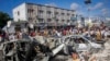 People walk amidst destruction at the scene, a day after a double car bomb attack at a busy junction in Mogadishu, Somalia, Oct. 30, 2022. 