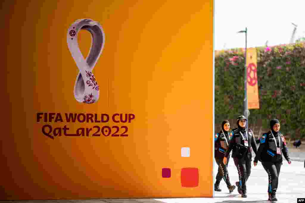 Policewomen walk past FIFA World Cup signs as they arrive at the Main Media Center (MMC) in Doha, ahead of the Qatar 2022 FIFA World Cup football tournament.
