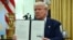 US President Donald Trump displays his signature on an Executive Order on reciprocal tariffs in the Oval Office of the White House in Washington, DC, on February 13, 2025.