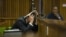 Oscar Pistorius covers his head with his hands and a notebook as he listens to forensic evidence during his trial in court in Pretoria, March 13, 2014. 
