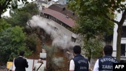 Les agents de la municipalité se tiennent à côté d'un appartement de quatre étages qui s'est effondré après un glissement de terrain après de fortes pluies qui ont frappé le district de Sutluce à Istanbul, le 24 juillet 2018.