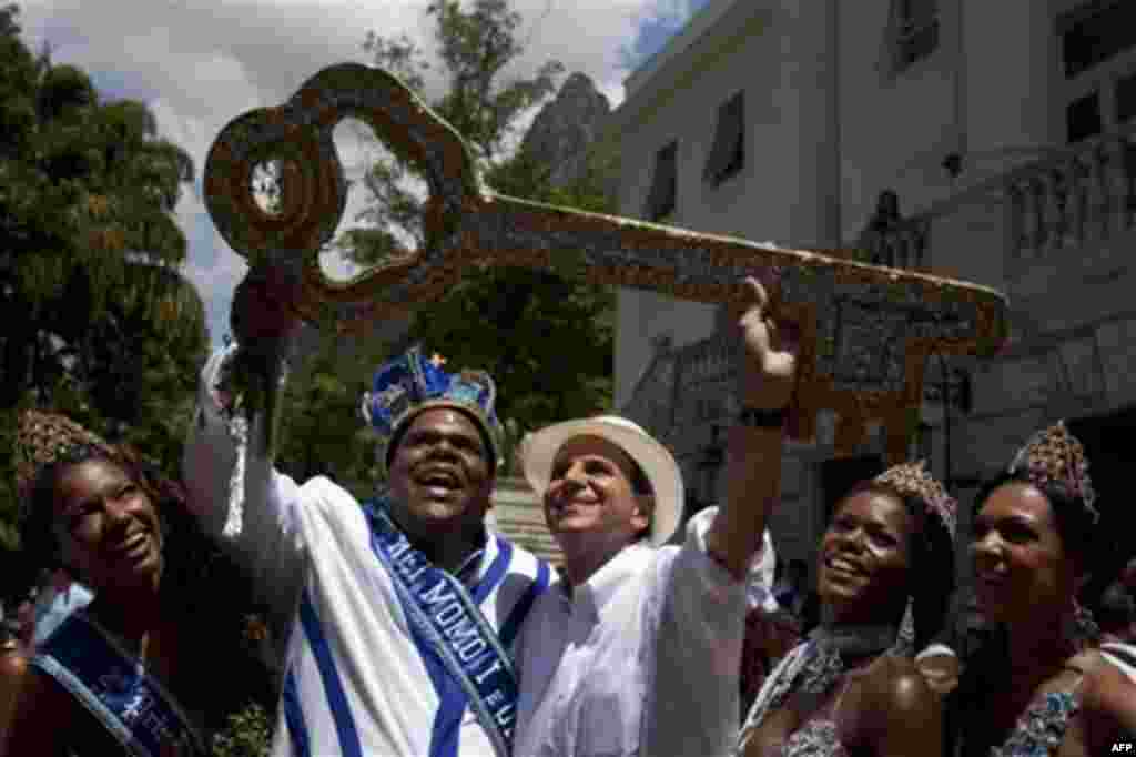 The mythical jester figure who reigns over Carnival, this year's King Momo; the crowned and costumed Milton Junior and Rio de Janeiro's Mayor Eduardo Paes hold up the key of the city at the official ceremony kicking off the five-day bash, in Rio de Janeir