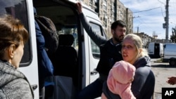 Una mujer con un niño sube a un autobús mientras evacuan a los civiles en Kramatorsk, Ucrania, el sábado 9 de abril de 2022. [Foto AP/Andriy Andriyenko]