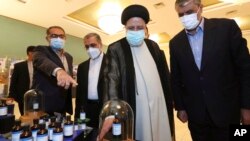 In this photo released by the official website of the office of the Iranian Presidency, President Ebrahim Raisi, second right, visits an exhibition of Iran's nuclear achievements in Tehran, Iran, April 9, 2022. 