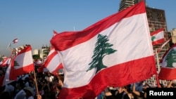 FILE - People carry national flags in Beirut, Lebanon, Aug. 4, 2021.