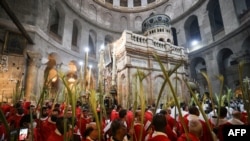 Roman Catholic clergy carry palm branches as they circle the aedicule during the Palm Sunday procession at the Church of the Holy Sepulchre in Jerusalem's Old City, Apr. 10, 2022.