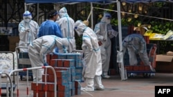 Workers wearing personal protective equipment (PPE) check food delivered by the local government for residents in a compound during a Covid-19 lockdown in the Jing'an district in Shanghai, China, April 10, 2022. 