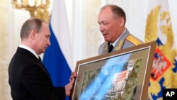 FILE - Russian President Vladimir Putin, left, receives a picture taken in Syria from Col. Gen. Alexander Dvornikov during an awarding ceremony in Moscow's Kremlin, Russia, March 17, 2016. 