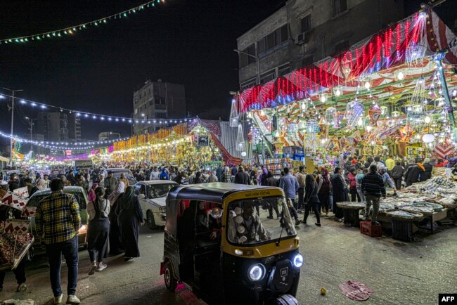 Sebuah tuk-tuk melewati pasar yang menjual lentera Ramadan dan dekorasi lainnya serta bahan makanan di distrik Sayyida Zeinab di ibu kota Mesir, Kairo, 30 Maret 2022, di tengah persiapan menjelang bulan suci Ramadan. (Khaled DESOUKI/AFP)