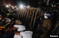 Police officers try to hold the metal barrier gates as demonstrators protest amid the country's economic crisis in Colombo, Sri Lanka, April 7, 2022.