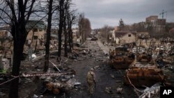 Seorang tentara Ukraina berjalan di tengah tank-tank Rusia yang hancur di Bucha, di pinggiran Kyiv, Ukraina, 6 April 2022. (Foto: Felipe Dana/AP)
