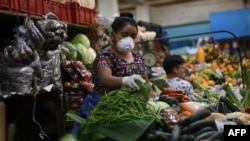 Una mujer indígena usa una mascarilla y guantes como medida preventiva contra el nuevo coronavirus, COVID-19, mientras vende verduras en el Mercado Central de la Ciudad de Guatemala, el 16 de marzo de 2020.