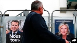 Muškarac prolazi pored plakata predsjedničke kampanje francuskog predsjednika Emmanuela Macrona i kandidata za reizbor i francuske krajnje desničarske predsjedničke kandidatkinje Marine Le Pen u Angletu, jugozapadna Francuska, 8. aprila 2022.