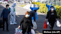 In this photo released by Xinhua News Agency, the first group of patients who have recovered from COVID-19 leave a makeshift hospital converted from Shanghai Convention & Exhibition Center of International Sourcing in Shanghai, China, April 9, 2022.
