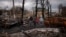 FILE - A family walks amid destroyed Russian tanks in Bucha, on the outskirts of Kyiv, Ukraine, April 6, 2022.