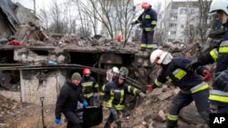 Tim SAR mengevakuasi mayat seorang penghuni gedung bertingkat yang hancur akibat serangan udara Rusia pada awal perang Rusia-Ukraina di Borodyanka, dekat Kyiv, Ukraina, 9 April 2022. (Foto: AP)