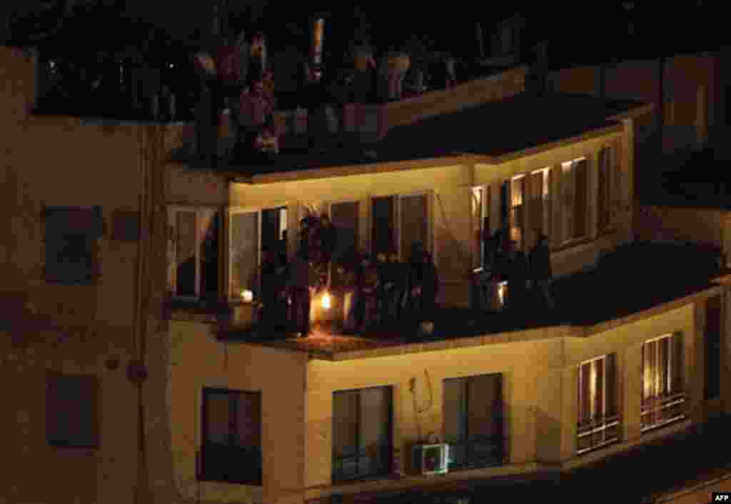 Pro-government demonstrators, gathered on the roof of a building, light a firebomb to throw it to anti-government demonstrators below, not seen, during clashes in Tahrir square, the center of anti-government demonstrations, in Cairo, Egypt, Wednesday, Feb