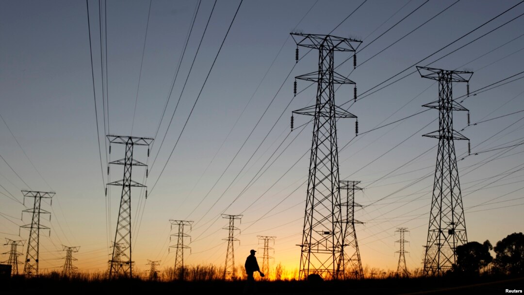 FILE - A man walks past electricity pylons as he returns from work in Soweto, outside Johannesburg.