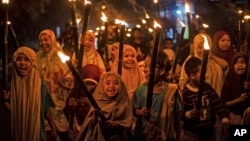 FILE - Muslim girls carry torches during a parade to celebrate the eve of Eid al-Fitr, the holiday marking the end of the holy fasting month of Ramadan, in Polewali Mandar, West Sulawesi, Indonesia, April 21, 2023.