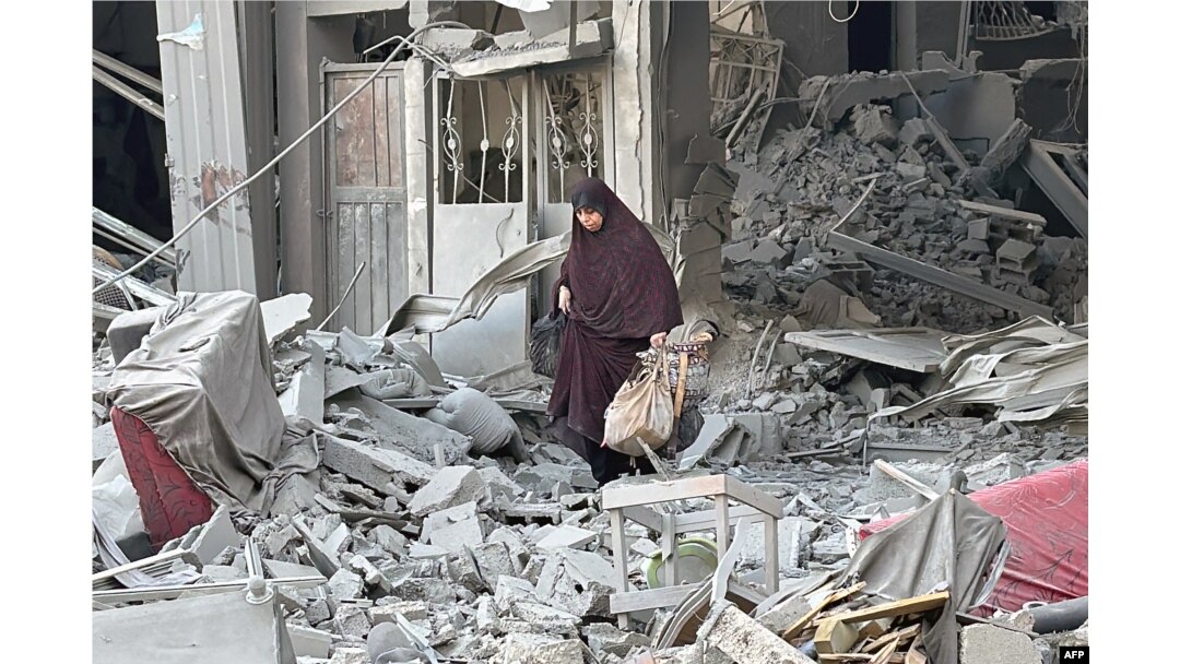 TOPSHOT - Seorang perempuan berjalan di atas reruntuhan bangunan menyusul serangan Israel di Beit Lahia di Jalur Gaza utara, 28 Oktober 2024. (AFP)